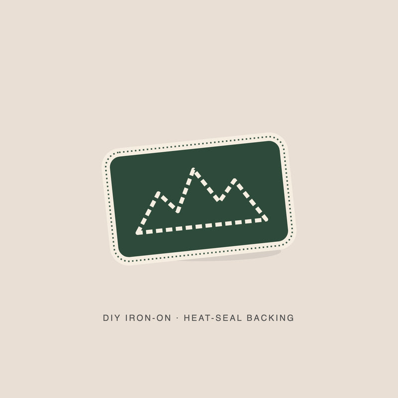 Illustration: Ridgeline mountain line as a green iron-on with a cream merrowed edge. Not a photograph.